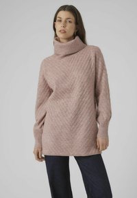 Light pink knitted sweater with a high ribbed collar and chevron pattern. Long sleeves, relaxed fit, and a textured finish.