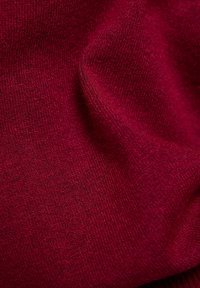 Weinroter Strickstoff mit weicher Textur, der eine leichte Dehnbarkeit und subtile Farbnuancen über die Oberfläche hinweg aufweist.