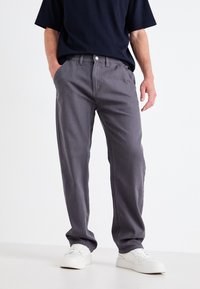 Grå chinos med rett kutt, med flat front, beltehefter og frontlommer, kombinert med hvite sneakers.