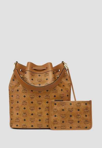 Sac seau en cuir brun clair et pochette assortie avec motif de diamants noirs et logo MCM, dotés d'une bandoulière et de finitions en métal doré.