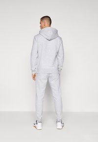 Gray hoodie with a large hood, ribbed cuffs and hem, paired with matching gray sweatpants. Featuring a smooth, textured fabric.