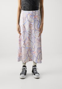 Hvit skjørt med et fargerikt paisley-mønster, med nyanser av blått, rosa og rødt. Kombinert med svarte høye sneakers og kremfargede sokker.