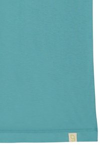 T-shirt turchese realizzato in un tessuto morbido e liscio. Presenta maniche corte e un orlo dritto con un piccolo cartellino logo di colore chiaro sul fondo.