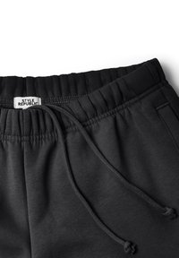 Schwarze Sweatpants aus Baumwollmischung mit elastischem Bund und Kordelzug. Verfügt über seitliche Taschen und ein Logo-Etikett. Glatte Textur.