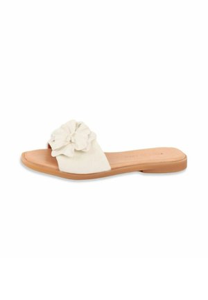 White slide sandal with tan sole and large fabric flower decoration on the strap, flat heel, open toe design.