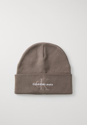 Brązowy dzianinowy beanie z mankietem. Posiada białe haftowane logo z napisem "Calvin Klein Jeans" oraz stylizowanym "CK". Gładka tekstura.