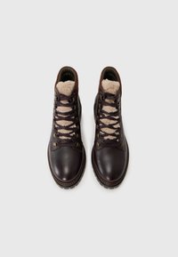 Bruine leren wandelschoenen met bontvoering, ronde neus, metalen oogjes en een gevoerd kraagje. Gestructureerd oppervlak en stevige rubberen zool.