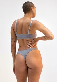 Grå bikini sæt med en bralette med justerbare stropper og matchende højtaljede bukser, lavet af glat, strækbart stof.
