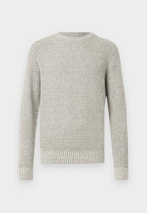 Lichtgrijze gebreide trui met een gestructureerd, geribbeld patroon. Heeft een ronde halslijn en lange mouwen, die eindigen met geribbelde manchetten en een geribbelde zoom.
