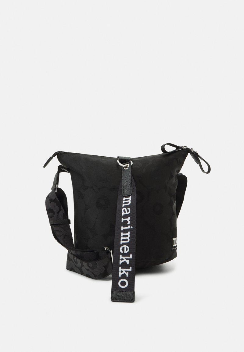 Borsa nera con motivo floreale, chiusura con zip, tracolla regolabile con testo "marimekko", texture morbida e design con la parte superiore curvata.