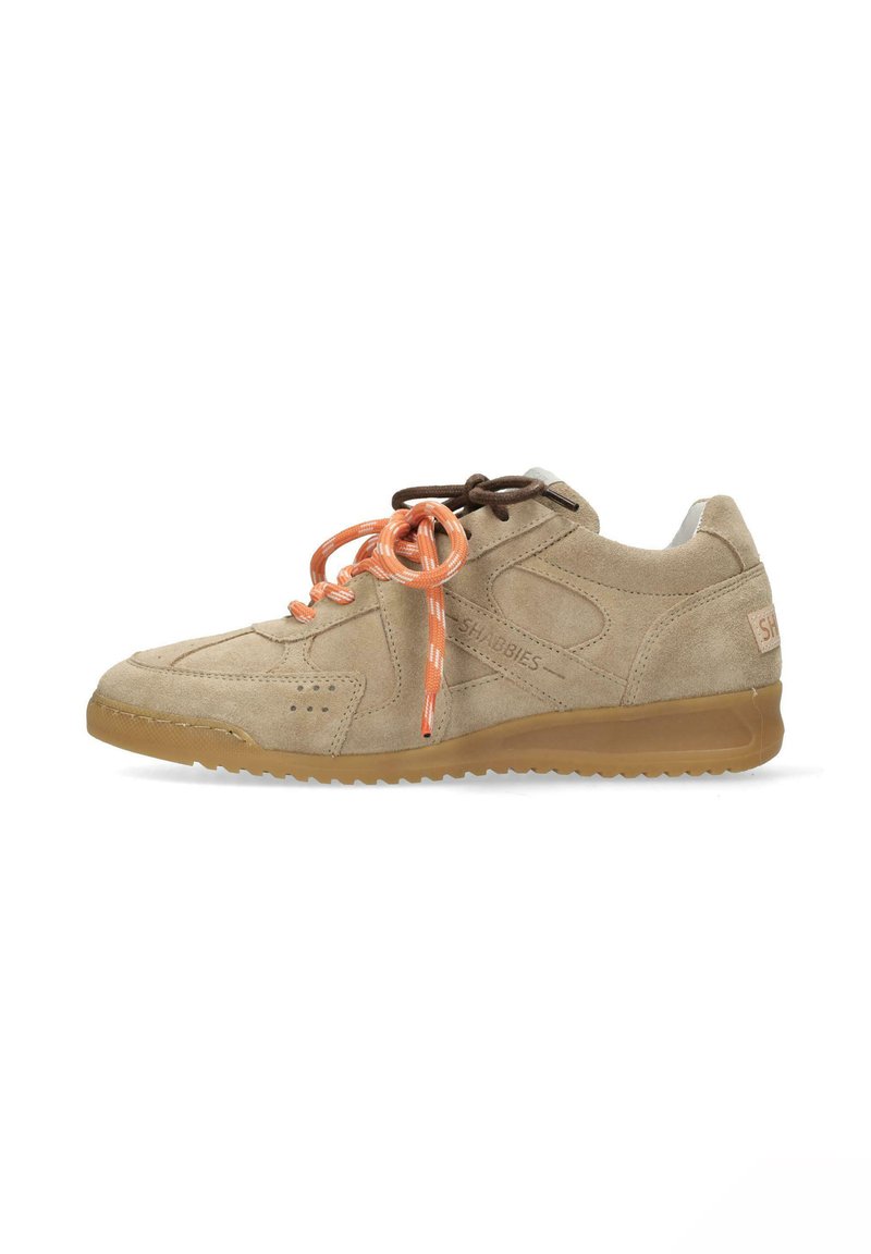 Zapatilla de ante beige con un diseño suave, cintas naranjas y marrones, detalles perforados y una suela de goma color tostado.