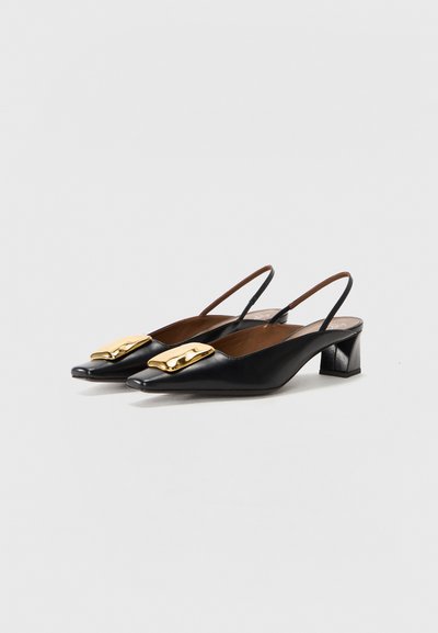 Black leather slingback heels with pointed toes, featuring a shiny gold decorative buckle. The heels have a small, block design.