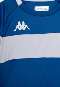 Camisola atlética azul com risca horizontal cinza, feita de tecido respirável. Apresenta o logo da Kappa em branco no canto superior esquerdo.