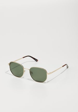 Occhiali da sole in metallo dorato con lenti verdi, forma geometrica, montatura sottile e punte scure marroni sulle astine. Cuscinetti nasali trasparenti visibili.
