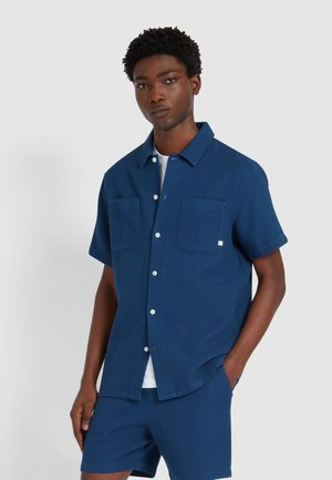 Kurzärmeliges, strukturiertes Hemd in Marineblau mit zwei Brusttaschen und Knopfleiste, kombiniert mit passenden Shorts. Leicht und lässig geschnitten.