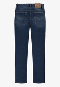 Jean en denim bleu foncé avec une coupe droite, dotée de deux poches arrière avec un motif à double couture et d'un patch en cuir griffé sur la taille.