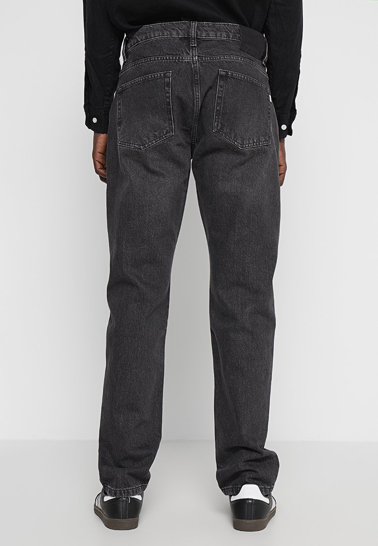 Zwarte denim jeans met een reguliere pasvorm, zichtbare achterzakken en een lichte vervaging. Draag ze met zwarte schoenen met witte accenten.