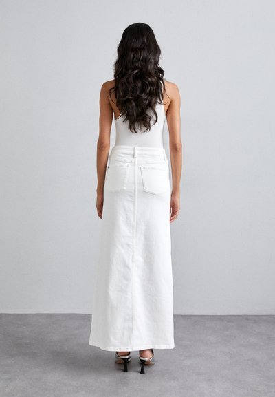 Falda maxi de denim blanca con bolsillos traseros, cintura con cinturón y corte recto, combinada con zapatos de tacón alto negros. Textura suave.