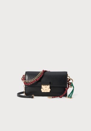 Bolso bandolera negro con cierre dorado, detalles de cadena dorada, detalles de cuerda roja y verde, y correa de cuero negra desmontable sobre fondo liso.