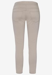 Pantalon beige ajusté avec poches arrière, jambes droites et taille mi-haute, présenté de dos sur un fond uni.