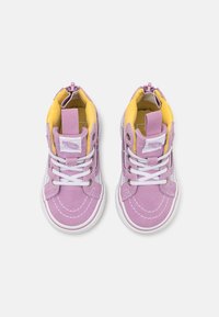 Baskets montantes violettes avec des lacets blancs, un intérieur rembourré jaune et des coutures contrastantes à l'extérieur. Fermeture éclair au niveau du talon.