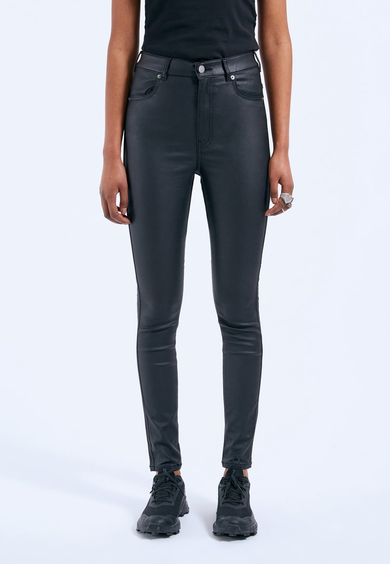 Jeans skinny in ecopelle nera con vita alta, chiusura a zip e bottone, tasche anteriori e posteriori, caratterizzati da una texture liscia e raffinata.
