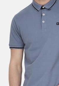 Blauwe poloshirt van katoen met een knoopsluiting met twee knopen, kraag in zwart en wit gestreept, en geborduurd logo op de borst.