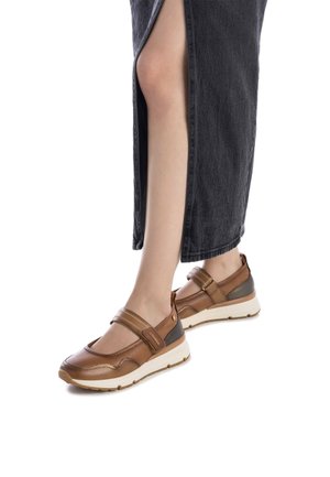 Zapatos de cuero marrón con una correa, punta redondeada y suela de goma; combinados con una falda de mezclilla negra con una abertura lateral.