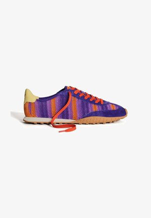 Zapatilla con estampado morado y naranja, con un upper texturizado, cordones naranjas, suela de goma y un acento en el talón amarillo.