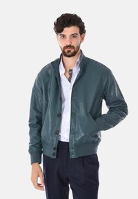 Giubbotto bomber in pelle teal con colletto alto, bottoni frontali e polsini a coste. Presenta una texture liscia e due tasche laterali.