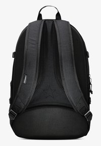 Svart ryggsekk med polstrede, justerbare stropper, teksturert stoff, en stjerne-logo på baksiden, og forsterkede sømdetaljer.