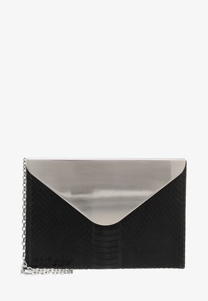 Pochette noire texturée avec grand rabat triangulaire argenté réfléchissant et bandoulière chaîne argentée sur fond blanc.
