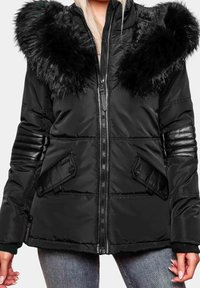 Giacca a vento nera con cappuccio in pelliccia sintetica, chiusura con zip, texture trapuntata e dettagli in pelle su maniche e tasche.