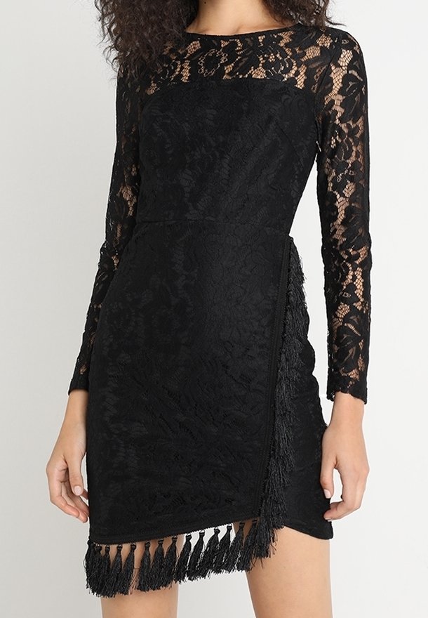 Robe en dentelle noire à manches longues, corsage ajusté, détail en franges à l'ourlet, et motifs floraux sur toute la robe. Texture douce et coupe moulante.