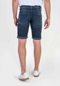 Pantalones cortos de mezclilla en azul oscuro con dobladillos enrollados, que cuentan con dos bolsillos traseros y una cintura con passantes para cinturón, diseñados para un look casual.