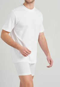 T-shirt en coton blanc à manches courtes et col rond, associé à un short blanc ajusté. Design simple, texture lisse et couleur unie.