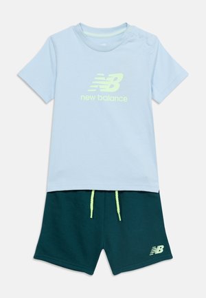 T-shirt à manches courtes bleu clair avec le logo "new balance" associé à un short vert foncé doté de cordons de serrage néon et d'un petit logo.