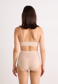 Set de sutien bej și chiloți cu talie înaltă, realizat dintr-un material neted, având bretele ajustabile și un logo subtil pe banda de la talie.