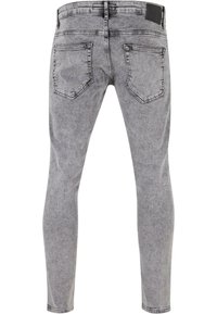 Slim-fit sivi traperice s izblijedjelim završetkom, stražnjim džepovima, prošivenim detaljima i crnim kožnim umetkom na pojasu.