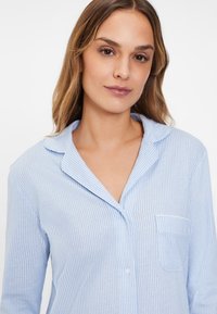 Hellblau-weiß gestreiftes Schlafhemd mit Kragen, einer Brusttasche und Knopfleiste. Weicher Stoff mit entspannter Passform.