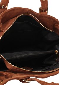 Intérieur d'un sac à main en cuir suédé marron, avec une doublure en tissu noir et une poche zippée avec quincaillerie dorée. Design ouvert, spacieux sans compartiments supplémentaires.