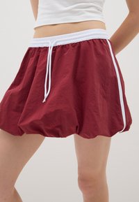 Gonna a palloncino leggera bordeaux con stringa bianca e strisce laterali, caratterizzata da una vita elastica arricciata e un tessuto testurizzato.