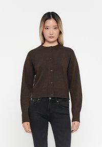 Bruine gebreide cardigan met een ronde hals, geribde manchetten en zoom, voorzien van een knoopsluiting aan de voorkant. Draag het over zwarte jeans.