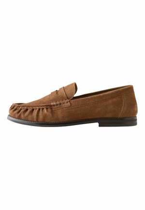 Mocassin pour homme en daim marron avec bout mocassin cousu et semelle plate noire, présenté de profil sur fond blanc.