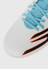 White soccer shoe featuring a textured upper, light blue laces, and a black and orange accent. Smooth finish with a streamlined shape.