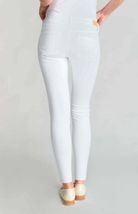 Vaqueros blancos ajustados hechos de una tela elástica con bolsillos traseros. Diseñados con una cintura alta y una textura suave. Estilo sencillo sin patrones visibles.