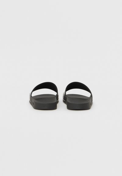 Sandales noires plates avec deux brides incurvées. Semelle intérieure texturée et semelle extérieure lisse. Design simple, léger et apparence minimaliste.