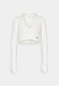 Biały krótki sweter z długimi rękawami, prążkowany materiał, dekolt w serek oraz mała naszywka z logo CK na przodzie. Klasyczny i dopasowany krój.