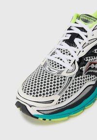 Close-up of a white, black, and neon green Saucony running shoe with mesh upper, white laces, and turquoise and yellow sole accents.