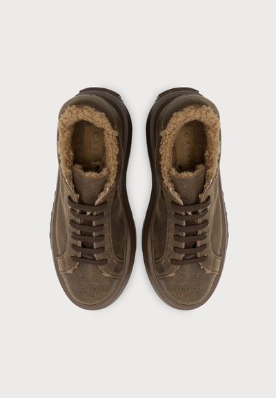 Paire de baskets en cuir marron avec doublure en fourrure et lacets marron foncé, vues de dessus sur fond blanc.